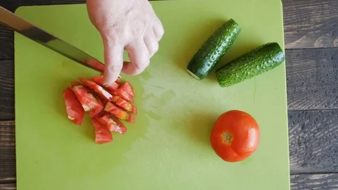 Cooking and home concept - close up of female hand cutting tomato on cutting boa Stock Footage 77159690