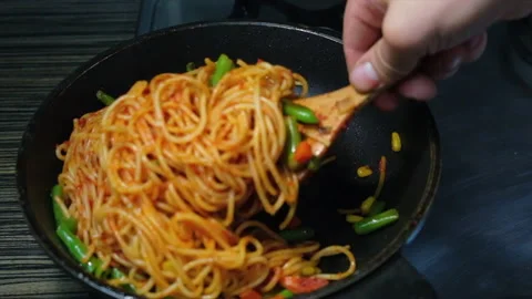 Cooking and stirring the spaghetti with vegetable in the frying pan Stock Footage 196418876