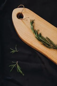 Cooking background concept. Close view of wooden cutting board with rosemary on Stock Photos