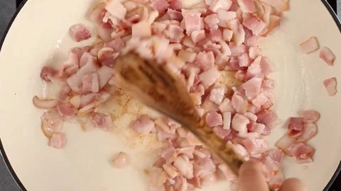 Cooking bacon in a cast iron pan with a wooden spoon top view Stock Footage 242524222