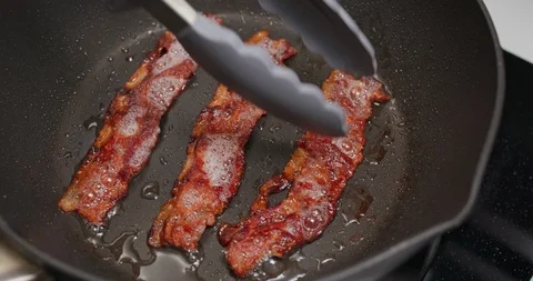 Cooking bacon on the fry pan in kitchen for breakfast Stock Footage 112476708
