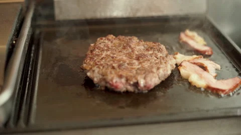Cooking bacon slice and beef cutlet for burgers on the grill, close-up. Chef in Stock Footage 264485841