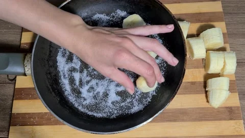 Cooking Bananas - Adding Bananas To Sugar In A Pan Stock Footage 164155707