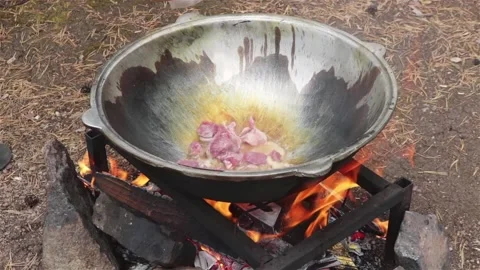 Cooking beef meat in large cauldron on fire outdoor Vidéo 115083215