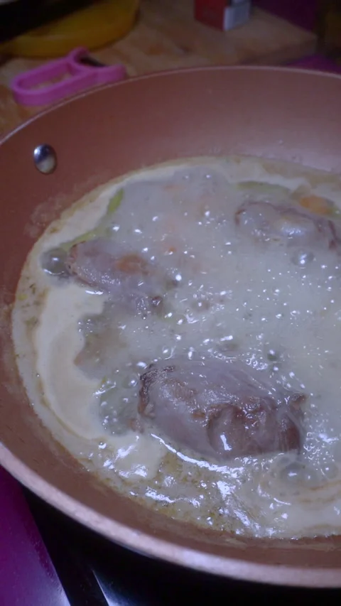 Cooking boiling lamb cheeks in a wok on a vitroceramic stove. Home cooking co Stock Footage 152648038