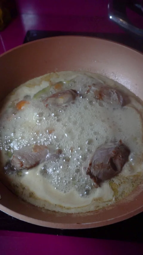 Cooking boiling lamb cheeks in a wok on a vitroceramic stove. Home cooking co Stock Footage 152648042