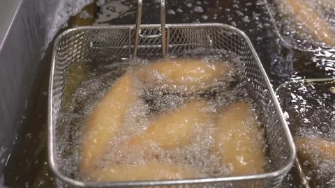 Cooking breaded chicken in deep fryer with hot boiling oil Stock Footage 79677539