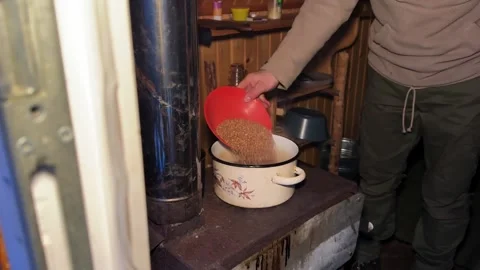 Cooking buckwheat in enameled pot on cast iron wood stove in cabin Stock Footage 336010310