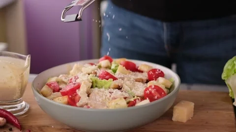 Cooking Caesar salad inside deep cooking bowl - pouring grated parmesan cheese Vídeos de archivo 198644293