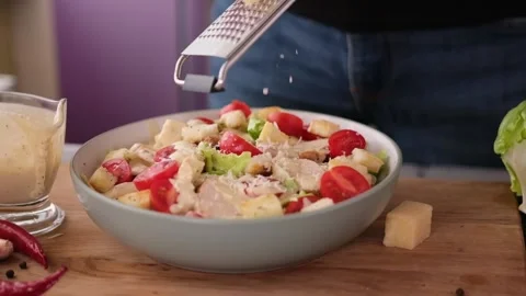 Cooking Caesar salad inside deep cooking bowl - pouring grated parmesan cheese Vídeos de archivo 198644360