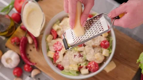 Cooking Caesar salad inside deep cooking bowl - pouring grated parmesan cheese Vídeos de archivo 198644391