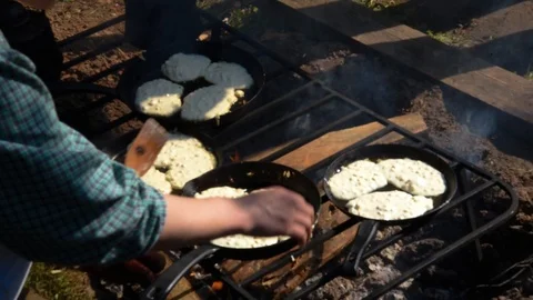 Cooking cakes in pans on an open fire. Stock Footage 117627345