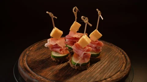 Cooking canapes, bread, cheese, jamon, ham, cucumber, canapes on skewers rotates Video stock 148640821