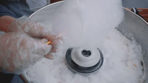 Cooking candy floss closeup. Young female hands in gloves wrap sugar on a stick. Stock Footage 116443307