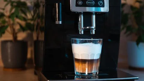 Cooking cappuccino in a coffee machine. Stock Photos