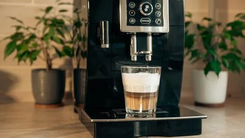 Cooking cappuccino in a coffee machine. Stock Photos