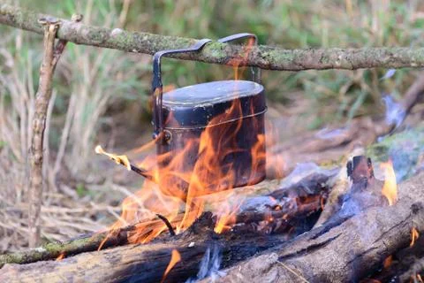 Cooking with cauldron on campfire. Stock Photos