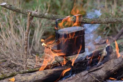 Cooking with cauldron on campfire. Stock Photos