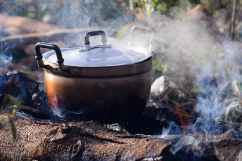 Cooking with cauldron on campfire. Stock Photos