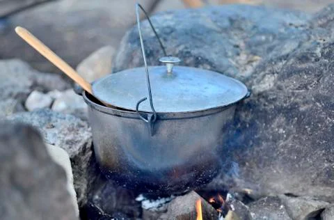 Cooking in a cauldron on an open fire. Preparing food at the stake in a wild  Stock Photos