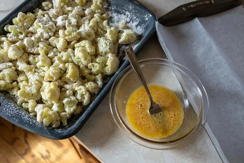 Cooking cauliflower with egg mixture in kitchen setting on a wooden table Stock Photos