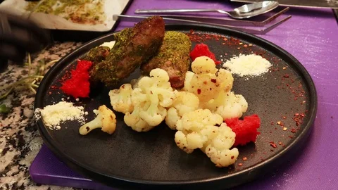 Cooking cauliflower in the kitchen. Chef. Black plate, dish decor.Meat 動画素材 129701541