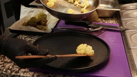 Cooking cauliflower in the kitchen. Chef. Black plate, dish decor.Meat Stock Footage 129701641