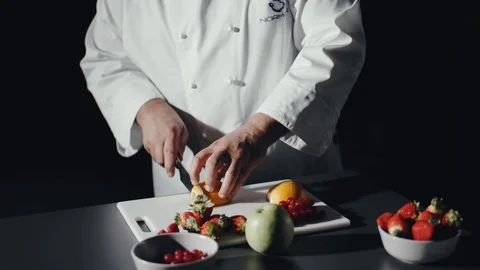 Cooking Chef Cuts Slice of Lemon on Black Table Filled with Fresh Fruits Video stock 119921716