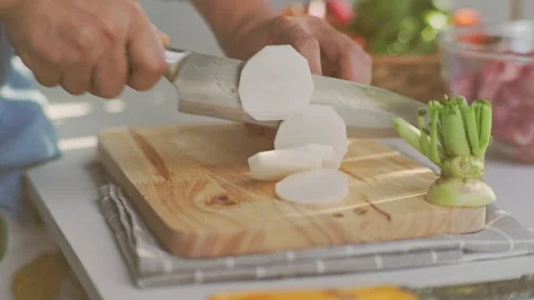 Cooking - Chef's hand cutting white radish on a chopping board in the kitchen. Stock Footage 242343449