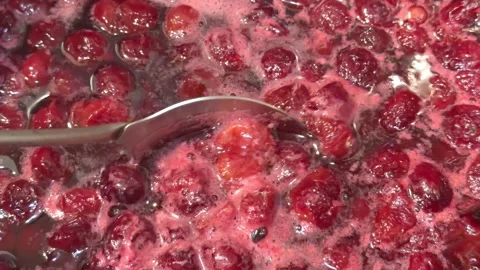 Cooking cherry jam while stirring with a spoon in boiling syrup in close up Stock Footage 337883283