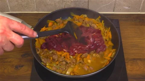 Cooking chicken gizzards with vegetables adding chicken liver into frying pan Vídeos de archivo 345422258