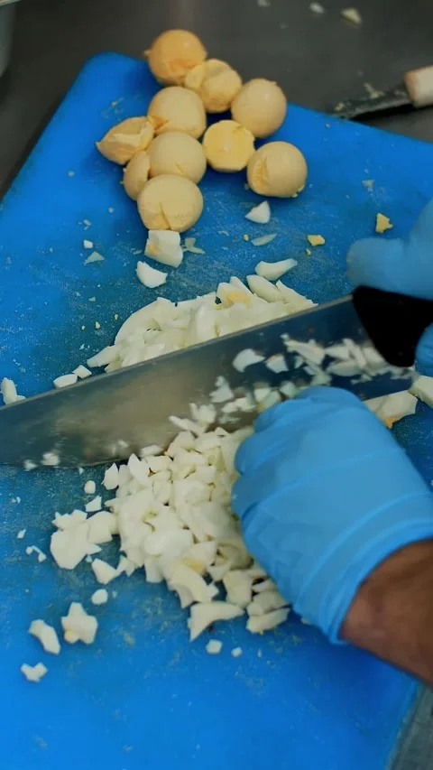 Cooking. close-up, the chef, in protective gloves, is cutting boiled eggs on Stock Footage 320771780