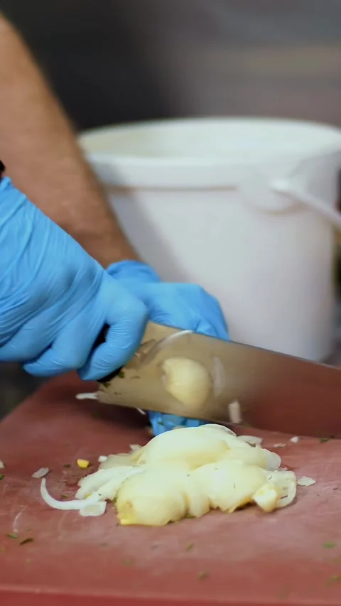 Cooking. close-up, the chef, in protective gloves, is cutting onion on cooking Stock Footage 321012841