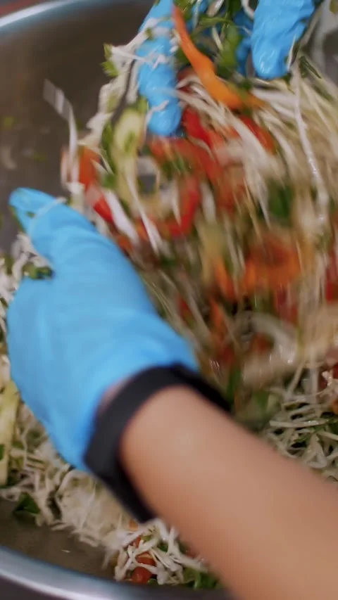 Cooking. close-up. the chef, in protective gloves, prepares a salad in a large Stock Footage 322978960