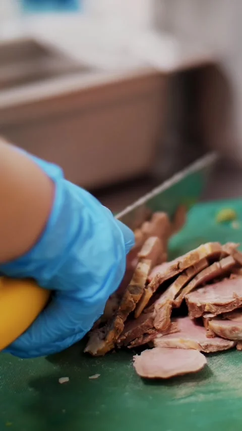 Cooking. close-up, the chef, in protective gloves, is cutting meat, boiled pork Stock Footage 323437450