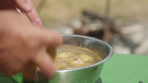 Cooking dinner while hiking in nature. Slicing vegetables on a board Stock Footage 144681049