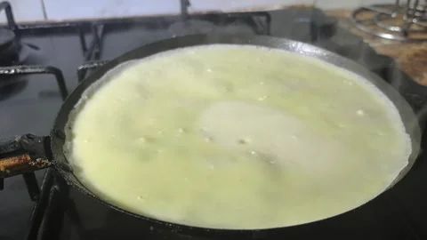 Cooking dosa on a hot pan in a kitchen at home for breakfast with simple ingredi Stock Footage 328443311