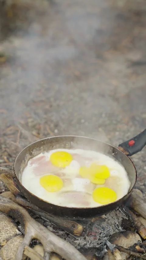 Cooking eggs in a frying pan while camping. A close-up of fried eggs in a pan 動画素材 307007864