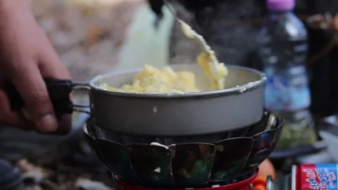 Cooking eggs over a frying pan in the wild Stock Footage