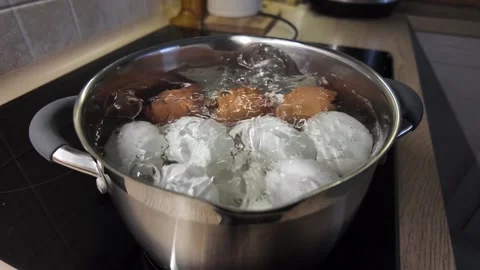 Cooking eggs in a pot on a stove in a kitchen at home Stock Footage 325418044