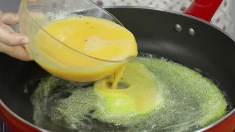 Cooking eggs in a red skillet in the kitchen Stock Footage 256038252