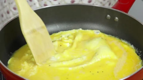 Cooking eggs in a red skillet in the kitchen Stock Footage 256038264