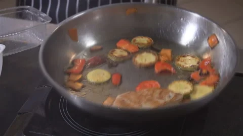Cooking on fire. The chef cooks vegetables and meat in a pan with the fire Stock Footage 98071883
