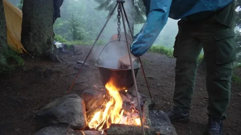 Cooking on a fire in the forest during the rain. Cooking on a camping trip. Stock Footage 217395156