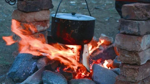 Cooking on a fire, strong wind blows the fire. Stock Footage 79453456