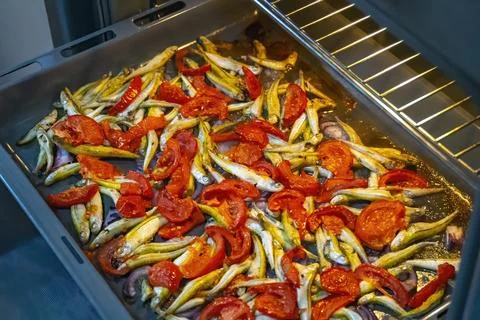 Cooking fish with cherry tomatoes and herbs on parchment in the oven Stock Photos