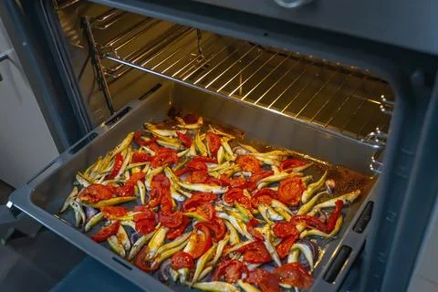 Cooking fish with cherry tomatoes and herbs on parchment in the oven Stock Photos