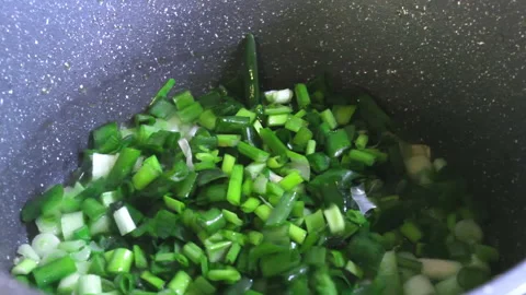 Cooking fresh spring onion, throwing chopped scalion in boiling olive oil Video stock 193597855