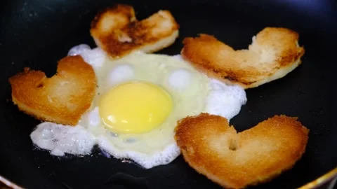 Cooking fried egg and bread  in the shape of heart  in a frying pan. 動画素材 283377904