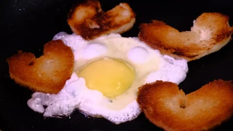 Cooking fried egg and bread  in the shape of heart  in a frying pan. Stock Footage 283383342